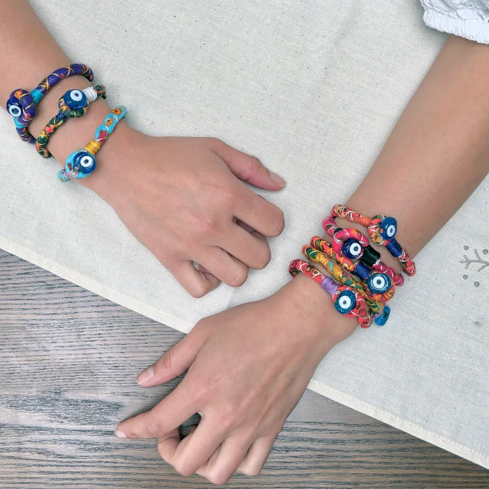 A woman wearing colourful handmade bracelets with evil eye bead detail