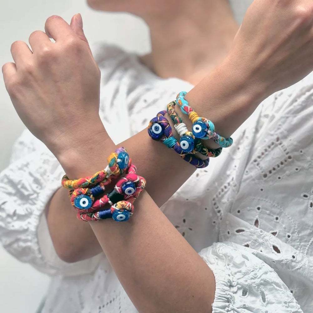 A woman in a white blouse wearing colourful handmade bracelets with evil eye bead detail