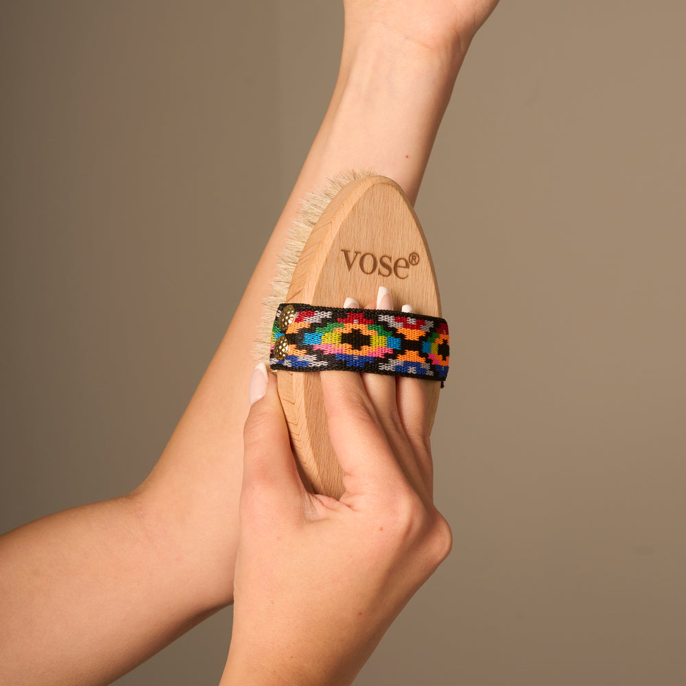 A woman using a Horse Hair Dry Body Brush with an elastic handle with bright coloured pattern on her arm