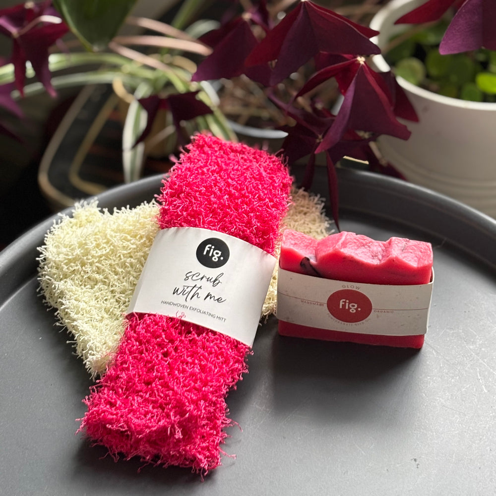 pink scrub and a soap bar on a gray surface with plants in the background