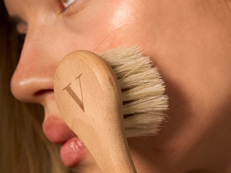 woman holding a horse hair face brush with a wooden handle