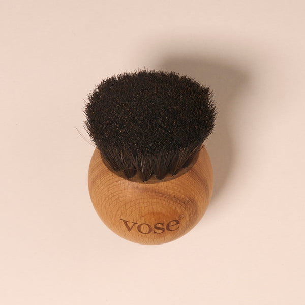 Round shaped black horse hair face brush on a pastel background