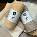 100% organic cotton herringbone patterned Turkish Towel in yellow colour on a table with different coloured towels