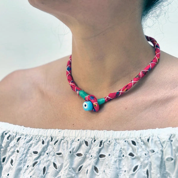 Red handmade necklace with evil eye bead detail on a woman's neck