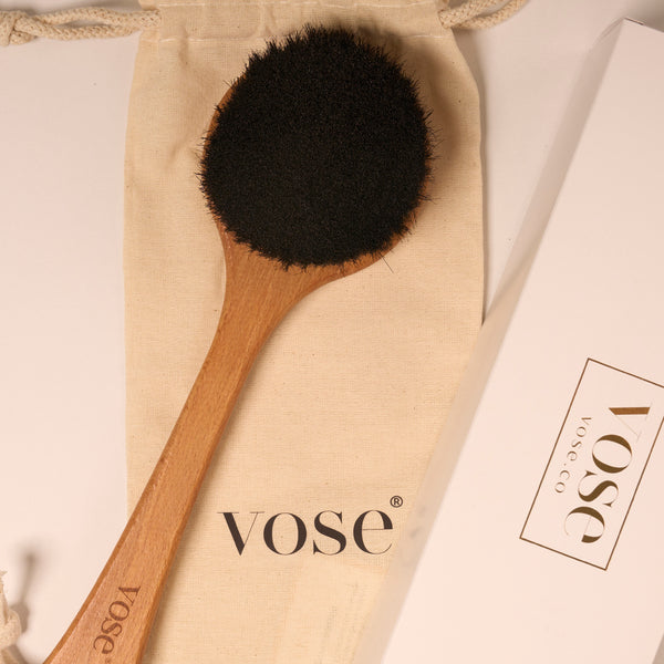 Black horse hair body brush with long handle on display with its cotton pouch and packaging