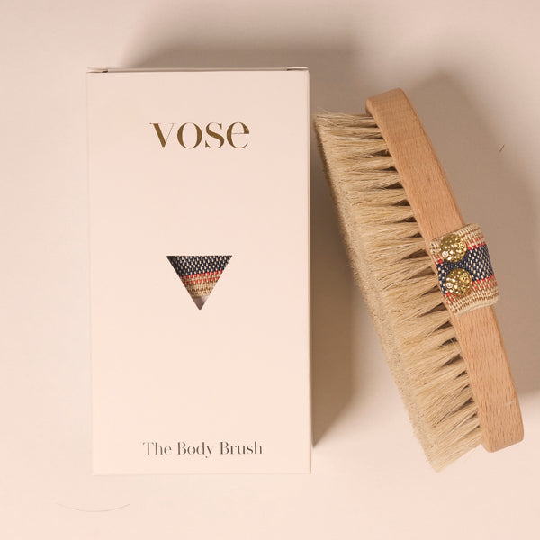 Horse Hair Dry Body Brush with a stripy elastic handle on display with its packaging 