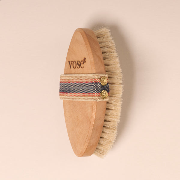 Horse Hair Dry Body Brush with a stripy elastic handle on a pastel coloured background