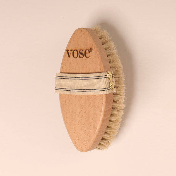 Horse Hair Dry Body Brush with a vanilla coloured elastic handle with thin black stripes on a pastel coloured background