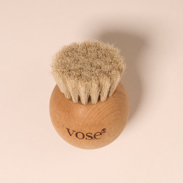 Round shaped white horse hair face brush on a pastel background