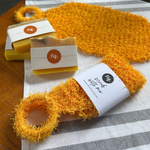Fig Wellbeing. handmade soap and natural loofah scrubber set on a striped cloth over a wooden table.