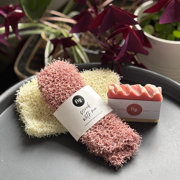 pink scrubs and a bar of soap on a gray surface with plants in the background